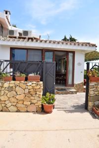 a house with a stone wall and a black door at Battistina Holiday Home in Monte Nai