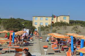 eine Gruppe von Menschen am Strand mit Sonnenschirmen in der Unterkunft Hotel Belmare in Marina di Grosseto