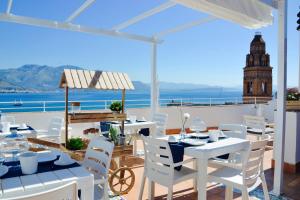 a restaurant with white tables and chairs and a clock tower at Il Bottone al Duomo in Gaeta