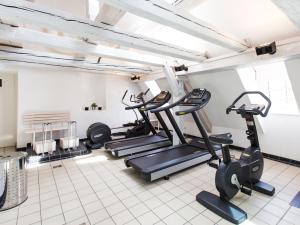 einen Fitnessraum mit Laufbändern und Crosstrainern in einem Zimmer in der Unterkunft DORMERO Hotel Villingen-Schwenningen in Villingen-Schwenningen