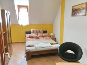 a bedroom with a bed and a black chair at AIDA Apartman in Gyula