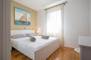 a bedroom with a white bed with a sailboat painting on the wall at Apartments Bo in Malinska