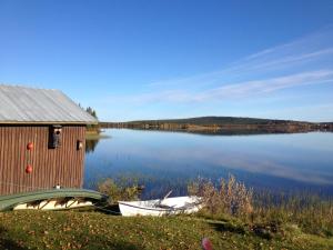 uma casa e dois barcos na margem de um lago em Lakeside House in Lapland em Skaulo