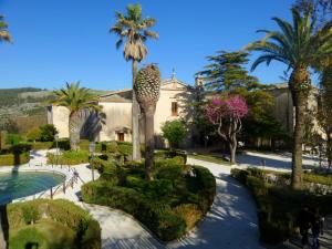 un complejo con palmeras y piscina en Antico Convento Dei Cappuccini, en Ragusa