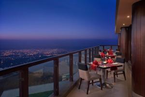 a dining table on a balcony with a view of the city at Sterling Mussoorie in Mussoorie