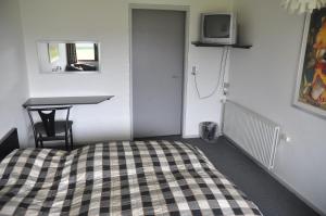 1 dormitorio con 1 cama, escritorio y TV en Hotel Lakolk, en Rømø Kirkeby
