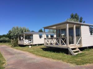 a mobile home with a large porch on a grass field at Camping Phare Ouest in Saint-Denis-dʼOléron