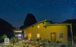 a building with a table and chairs at night at Yangshuo Yunshe Mountain Guesthouse in Yangshuo