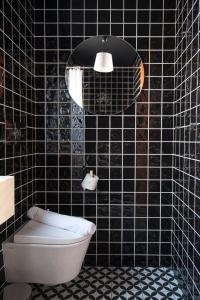 a bathroom with a toilet and a black tiled wall at Lemon Tree Stay in Faro