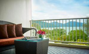 a table with a book on a balcony with a couch at PARKROYAL Penang Resort in Batu Ferringhi