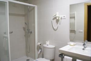 a bathroom with a shower and a toilet and a sink at Hotel Gema in Almadén