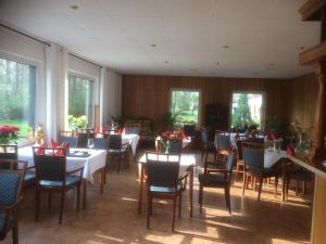 a dining room with tables and chairs and windows at Pension Seeterrasse in Serwest
