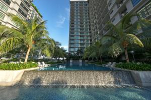 a swimming pool with a waterfall and palm trees at Acappella Suite Hotel, Shah Alam in Shah Alam