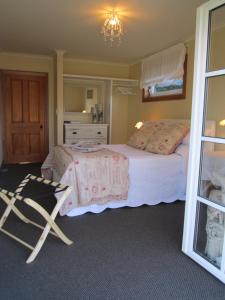 een slaapkamer met een bed en een stoel erin bij Magnolia Cottage in Christchurch