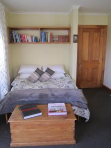 a bedroom with a bed and a table with books at Magnolia Cottage in Christchurch