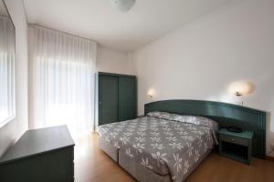 a bedroom with a bed with a green headboard at Aparthotel La Pineta in Lido di Jesolo