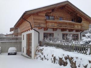 a wooden house in the snow with a fence at Ado's Haus in Niederau