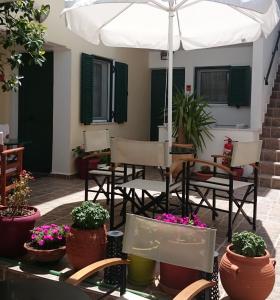 a patio with chairs and potted plants and an umbrella at 9 Muses in Elafonisos