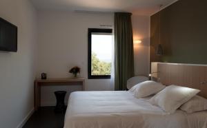 1 dormitorio con 1 cama con sábanas blancas y ventana en Résidence Hôtelière Alcyon, en Porto Vecchio