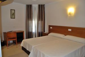 Un dormitorio con una cama, una mesa y un escritorio. en Hotel Gema, en Almadén