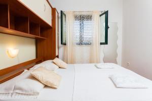 1 dormitorio con cama blanca y ventana en Apartments Marija, en Vela Luka