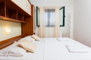 a bedroom with a white bed and a window at Apartments Marija in Vela Luka