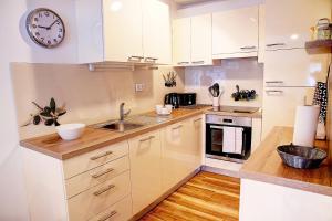 a kitchen with white cabinets and a clock on the wall at Apartment Vita near Terme Paradiso in Dobova