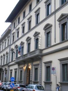 un grand bâtiment blanc avec des voitures garées devant lui dans l'établissement Hotel Giglio, à Florence
