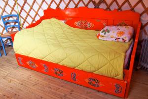 Cama naranja en habitación con silla azul en Camping Kerlaudy Mer et Yourtes, en Plouénan