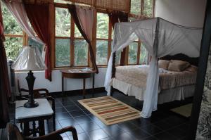 ein Schlafzimmer mit einem Himmelbett in einem Zimmer mit Fenstern in der Unterkunft Forres Park Nature Retreat in Mavis Bank