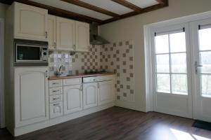 a kitchen with white cabinets and a window at Vakantiehuis NamaStee in Schoonloo