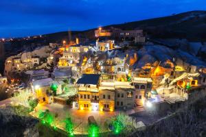 grupa domów na wzgórzu w nocy w obiekcie Cappadocia Gamirasu Cave Hotel w mieście Ayvalı