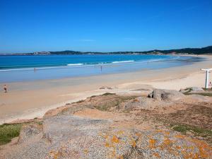a beach with people walking on the sand and the water at A Casa De Amparo in Sanxenxo