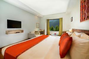 1 dormitorio con 1 cama grande con manta naranja en Sterling Manali, en Manali