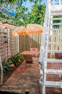 een patio met een oranje paraplu en een tafel met een ladder bij Cobie Apartment in Stellenbosch