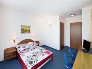 a room with a bed and a desk and a television at La Residence Kasandra in Jastrzębia Góra