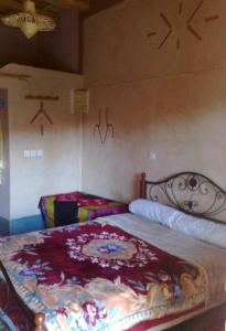a bedroom with a bed with a blanket on it at Auberge Des Jardins du Dades in Boumalne