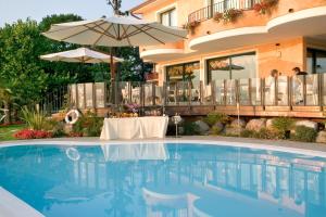 a swimming pool with a table and an umbrella at Hotel La Rondine in Sirmione