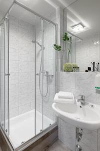 baño blanco con ducha y lavamanos en sleepIN, en Ingolstadt