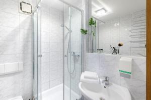baño blanco con ducha y lavamanos en sleepIN, en Ingolstadt