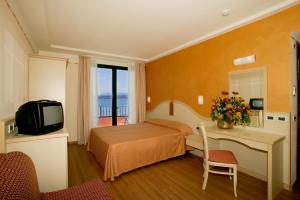 a hotel room with a bed and a desk and a television at Hotel La Rondine in Sirmione