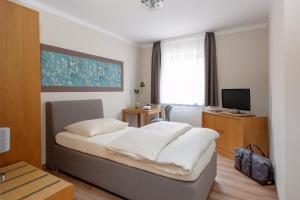 Dormitorio pequeño con cama y TV en sleepIN, en Ingolstadt