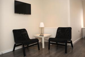 ロンドンにあるゲスト ハウス ロンドンの黒い椅子2脚、テーブル(壁にテレビ付)