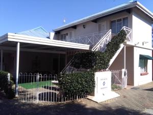 a white house with a staircase in front of it at Victorian Lodge in Bloemfontein