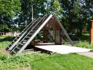 una estructura de madera con una escalera sobre el césped en Stichting Veenloopcentrum Weiteveen en Weiteveen