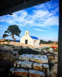 a small white chapel on a hill with a tree at Anatoli in Ambelas