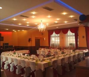einen Bankettsaal mit weißen Tischen und Stühlen sowie einem Kronleuchter in der Unterkunft Gaststätte Schwenksaal in Bayreuth