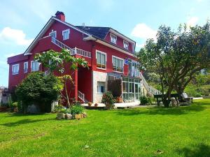 ein großes rotes Haus auf einem grünen Rasen in der Unterkunft Pensión Casa Elena in Reinante