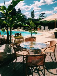 un patio con mesa, sillas y piscina en Hotel La Chaumette, en Privas