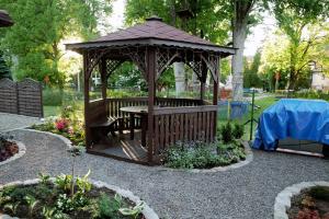 a wooden gazebo with a table in a garden at Willa San Remo in Kudowa-Zdrój